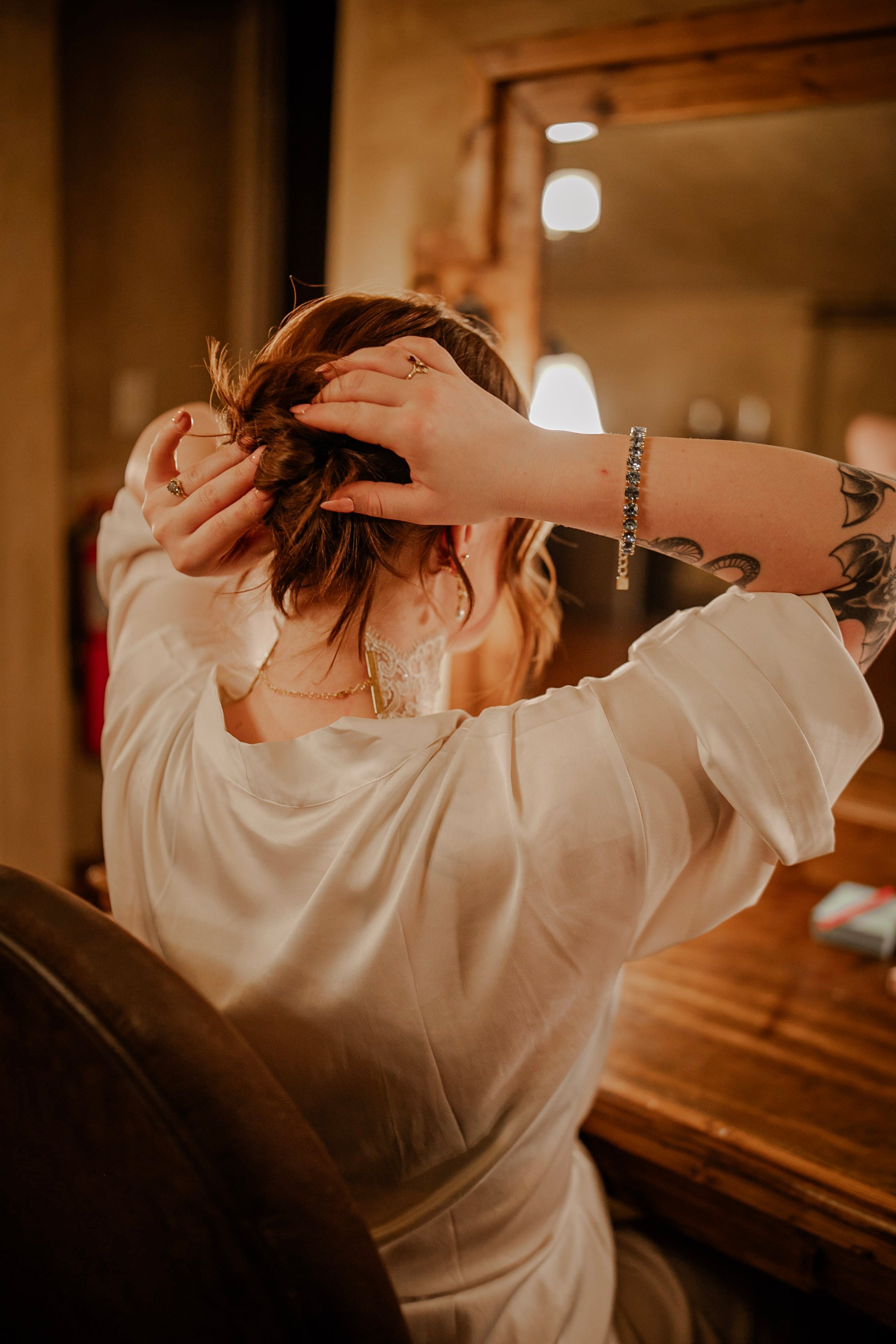 Lili Barker wearing her hair in a soft, textured updo, seen from behind at a salon mirror
